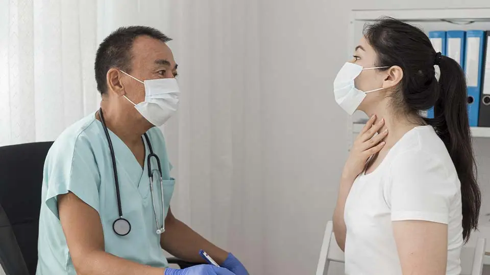 Doctor atiende a paciente. Ámbos llevan mascarilla