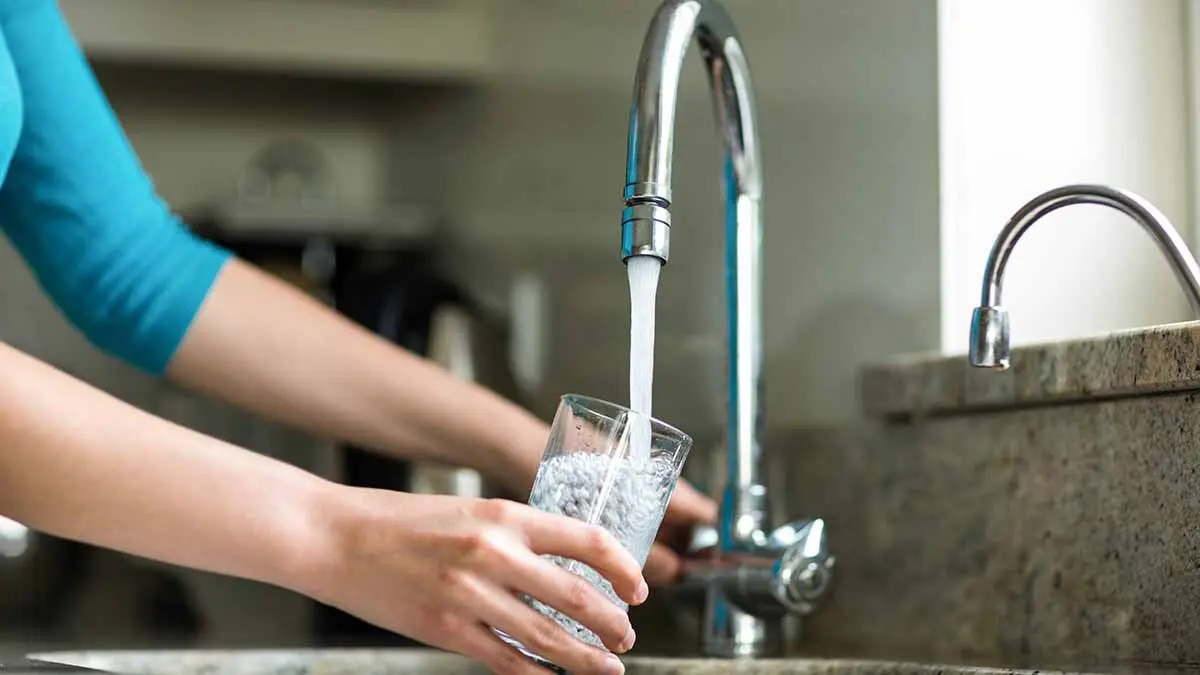 Una mujer llena un vaso de agua del grifo. Foto: Freepik