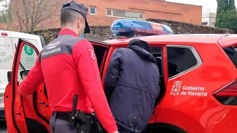 un agente de la Policía Foral introduce a un detenido en el coche patrulla