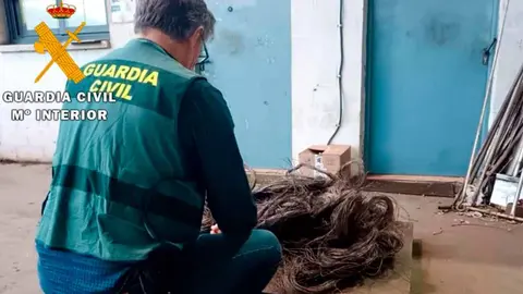 Un agente de la Guardia Civil junto a parte del cable telefónico de cobre recuperado durante la operación Cabatel